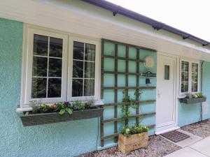 uma casa azul com duas janelas e plantas nela em Honeysuckle Cottage em Llandrindod Wells
