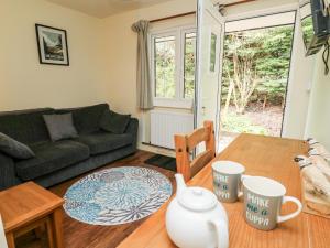 a living room with a table and a couch at Honeysuckle Cottage in Llandrindod Wells