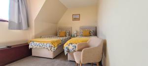 a small room with two beds and a chair at Braelea in Spean Bridge