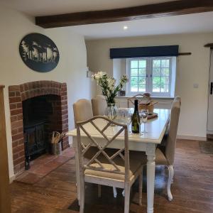 a dining room with a table and a fireplace at Brook Cottage in Kelling