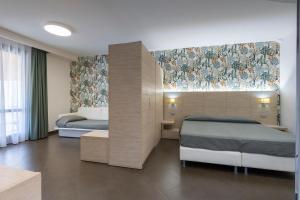a bedroom with two beds and a wall with flowers at Alaba Hotel in San Vito lo Capo