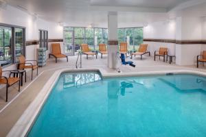 a pool in a hotel room with chairs and tables at Courtyard by Marriott Charleston Downtown/Civic Center in Charleston