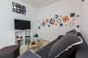 a living room with a gray couch and a flat screen tv at Apartments Viljac in Trogir