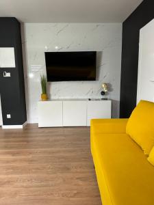 - un salon avec un canapé jaune et une télévision dans l'établissement Apartamenty Avia - Energylandia Zator, à Spytkowice