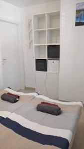 duas camas num quarto com paredes brancas e prateleiras brancas em Apartma Ela em Koper