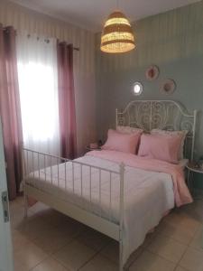 a bedroom with a bed with pink sheets and a chandelier at Fillitsa's Sweet Home in Neos Marmaras