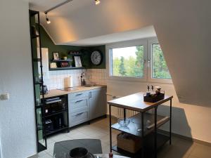 a kitchen with a table and a sink and a window at BOSTEL 1 - Modernes Dachgeschoss-Studio in Duisburg Meiderich, 4,7 km Hbf, U-Bahn 250m, Flughafen Düsseldorf 28 km, Landschaftspark 2,9 km, 5 Gehminuten von Herzklinik entfernt in Duisburg