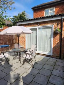 une terrasse avec une table, des chaises et un parasol dans l'établissement Home away from Home, à Woolwich