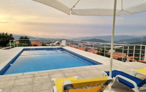 a swimming pool on the roof of a house with chairs and an umbrella at Quinta da Gandarela in Tarouca