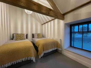two beds in a room with a window at Luxury Barn Conversion Perfect for Family Getaways in Foggathorpe