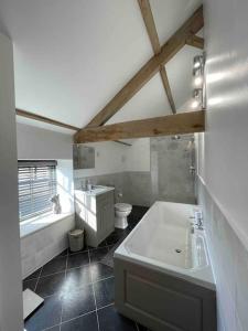a bathroom with a tub and a sink and a toilet at Luxury Barn Conversion Perfect for Family Getaways in Foggathorpe