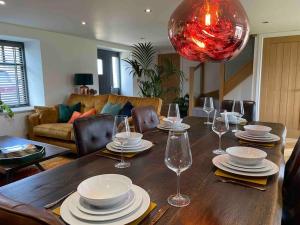 a dining room table with plates and wine glasses at Luxury Barn Conversion Perfect for Family Getaways in Foggathorpe