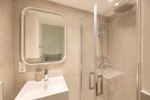 a bathroom with a sink and a shower with a mirror at Great 2-room apartment in Berlin