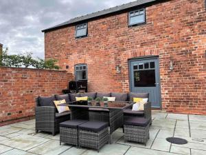 a patio with a couch and chairs in front of a brick building at Luxury Barn Conversion Perfect for Family Getaways in Foggathorpe