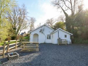 un edificio bianco con recinzione e tavolo da picnic di Mill House Cottage a Pwllheli