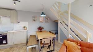 a kitchen and dining room with a table and a staircase at 19 Strawberry Hill, Tolroy Manor in Hayle