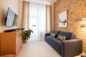 ein Wohnzimmer mit einem blauen Sofa und einer Ziegelwand in der Unterkunft Great 2-room apartment in Berlin