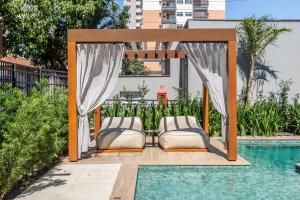 a gazebo with two beds next to a pool at Charlie Connect PUC in Porto Alegre