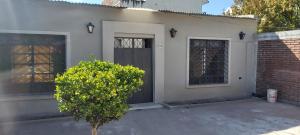 una casa blanca con una puerta negra y un arbusto en San Andrés en Salta