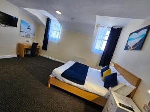 a bedroom with a bed and a desk and windows at Elsinore Hotel Llandudno in Llandudno