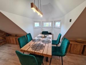 uma sala de jantar com uma mesa de madeira e cadeiras verdes em Apartament Ptasia Ostoja - 5D Apartamenty em Świeradów-Zdrój