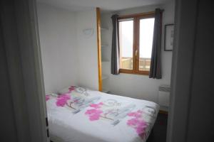 um quarto com uma cama com flores cor-de-rosa em Apt les luges pour 4 à 6 pers vue vallée wifi em Besse-et-Saint-Anastaise