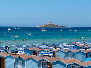 a beach with a bunch of people in the water at casa delle rose in Isola delle Femmine