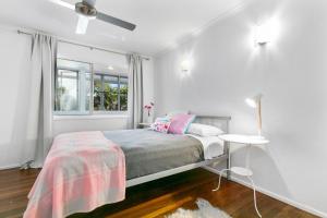 a white bedroom with a bed and a window at 5 Plover Street Peregian Beach in Peregian Beach