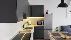 a kitchen with black cabinets and a sink and a table at KaLea Pula Center in Pula