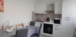 a kitchen with a table with chairs and white cabinets at Casa Vacanze Ale e Gio in Piombino