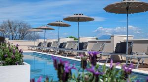 einen Pool mit Stühlen, Tischen und Sonnenschirmen in der Unterkunft Hotel Alfieri in Sirmione