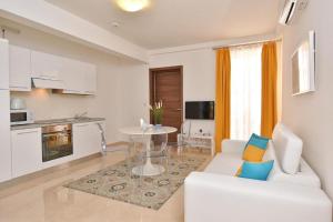a living room with a white couch and a kitchen at The Caves Apartments in St. Julianʼs
