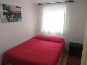 a red bed in a room with a window at Tormalyn Spa in Coquimbo