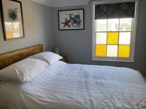 a bedroom with a white bed with two windows at Paragon Home in Ramsgate