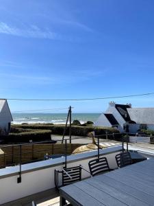a deck with a table and chairs and the ocean at La Cabane des Pêcheurs in Quiberon
