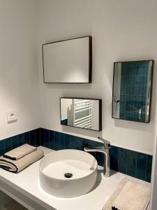 a bathroom with a white sink and two mirrors at La Cabane des Pêcheurs in Quiberon