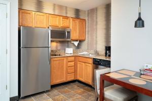 cocina con armarios de madera y nevera de acero inoxidable en Residence Inn New Bedford Dartmouth, en North Dartmouth