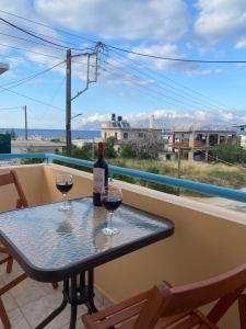 a table with two glasses of wine on a balcony at Kisamos Nice Apartment 3 in Kissamos
