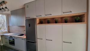Una cocina con gabinetes blancos y un refrigerador de acero inoxidable. en Apartament w Centrum, en Częstochowa 6 fotos más