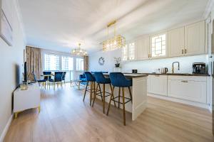a kitchen with white cabinets and blue bar stools at Nowa Letnica Apartament in Gdańsk