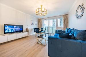 a living room with a blue couch and a tv at Nowa Letnica Apartament in Gdańsk