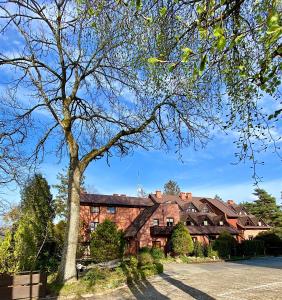 una gran casa de ladrillo con un árbol delante en Apartamenty Marea Rentals przy Promenadzie Słońca Poddąbie, en Poddąbie