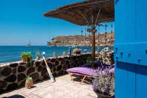 a patio with a purple chair and an umbrella and the ocean at Serenity Blue (Cave house) in Akrotiri