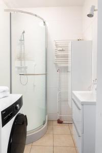 a white bathroom with a shower and a sink at G15 Apartment in Olsztyn