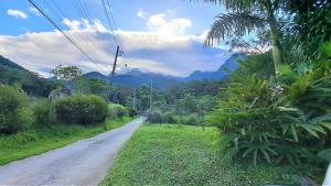 eine unbefestigte Straße mit Bergen in der Ferne in der Unterkunft Paradisíaco, piscina e churrasqueira em Guapi. in Guapimirim