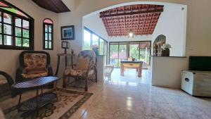 ein Wohnzimmer mit Stühlen und einem Tisch in der Unterkunft Paradisíaco, piscina e churrasqueira em Guapi. in Guapimirim