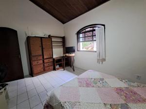 a bedroom with a bed and a window and a desk at Paradisíaco, piscina e churrasqueira em Guapi. in Guapimirim