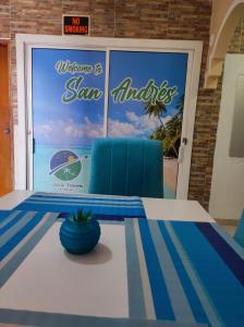 uma mesa com uma cadeira azul em frente a uma porta em Alojamientos Laila Sai y Zaida em San Andrés