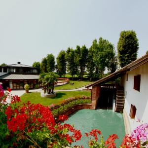 - une piscine dans une cour ornée de fleurs rouges dans l'établissement Hotel Novarello Resort & Spa, à Granozzo con Monticello