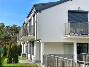 a white house with a balcony and a fence at Apartamenty Marea Rentals przy Promenadzie Słońca Poddąbie in Poddąbie